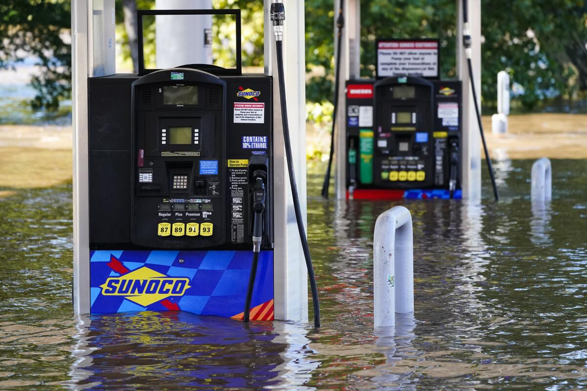 Sunoco gas pumps sit partially submerged in flood waters.