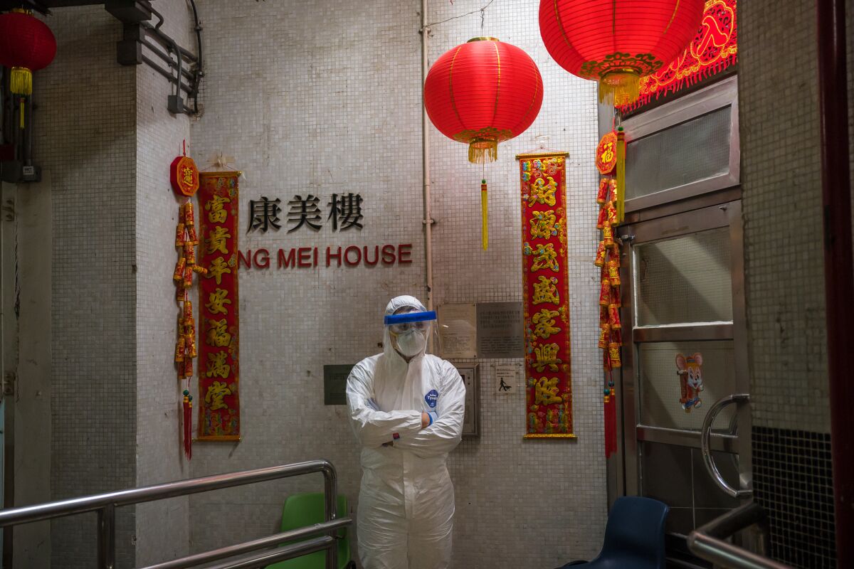 An official in protective gear stand guard outside the Hong Mei House in Hong Kong.