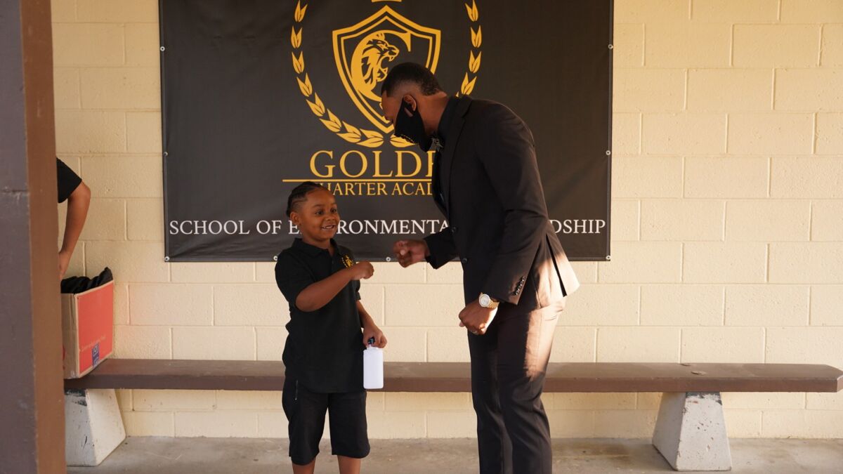 Golden Charter Academy CEO Robert Golden shares a fist bump with a student.