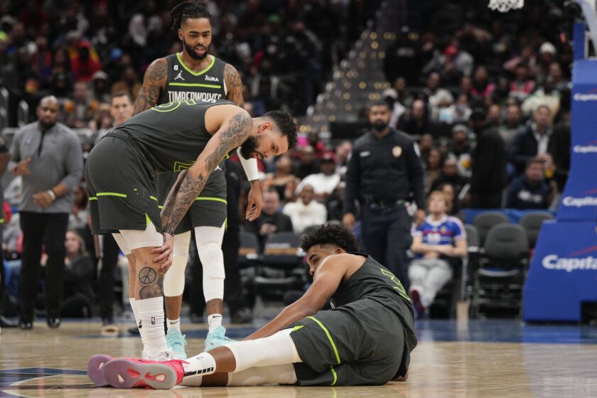 Minnesota Timberwolves guard Austin Rivers, left, checks on center Karl-Anthony Towns (32) after he got hurt during the second half of an NBA basketball game against the Washington Wizards, Monday, Nov. 28, 2022, in Washington. (AP Photo/Jess Rapfogel)