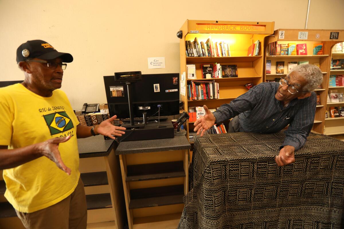 James Fugate, co-owner of Eso Won Books, right, discusses the recording, with Clint Rosemond inside the bookstore.