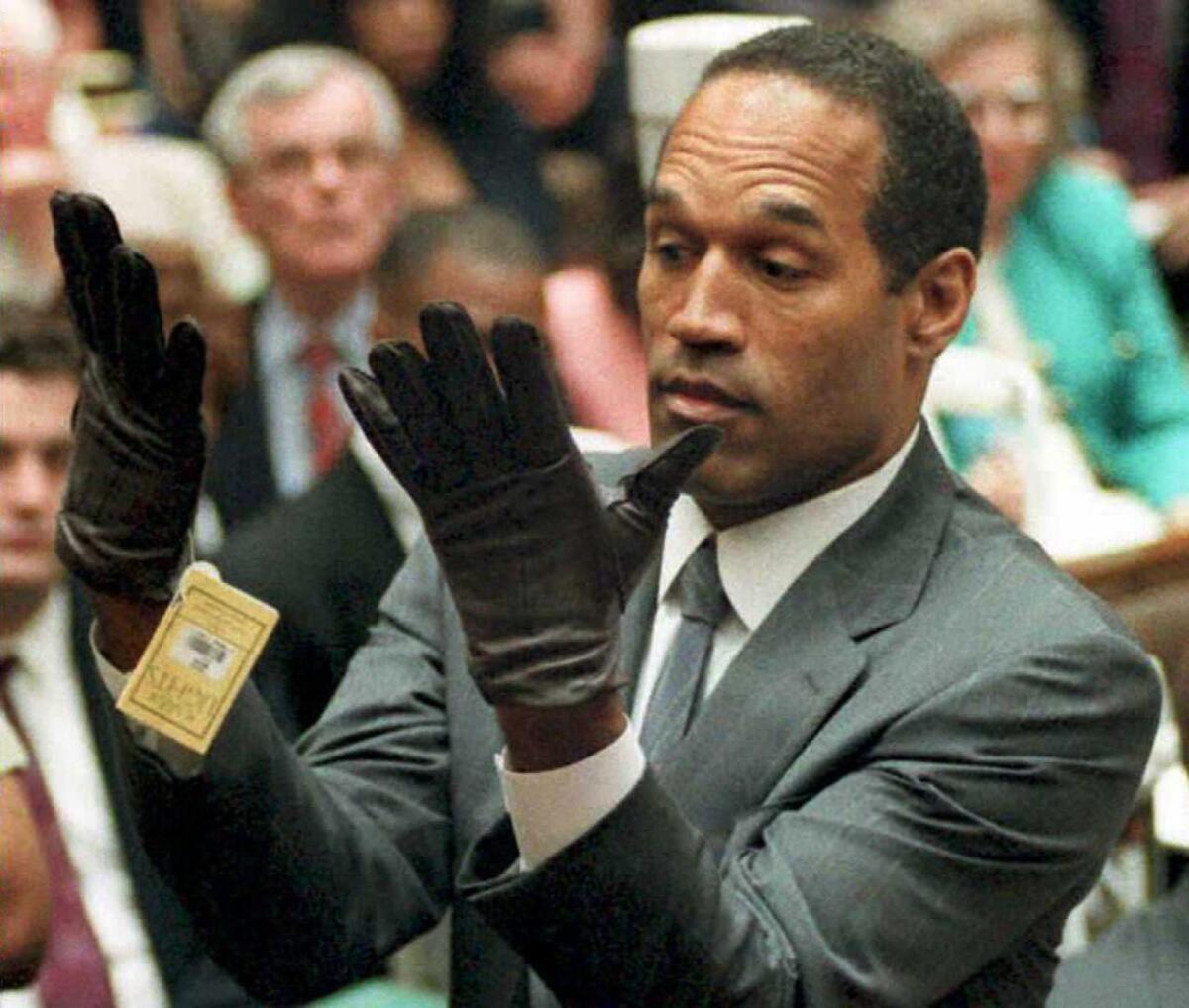 This Nov. 30, 1995, file photo shows former football player and actor O.J. Simpson looking at a new pair of Aris extra-large gloves that prosecutors had him put on during his double-murder trial in Los Angeles.