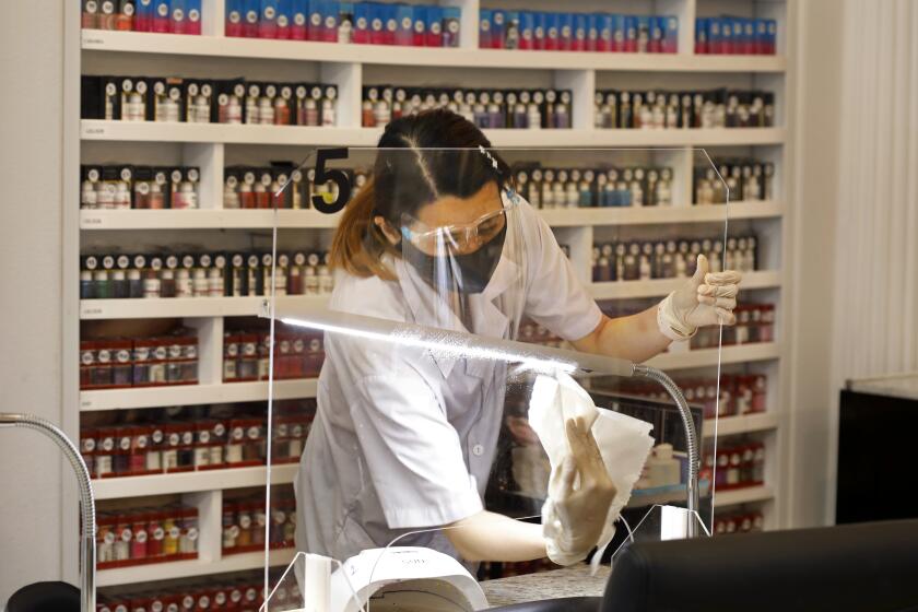 FULLERTON,CA-JUNE 19 2020--Manicurist Amy Pham wears a mask and protective shield while doing her work, which she says she is used to already. Each station must be thoroughly cleaned between clients. Captivate Nail & Spa in Fullerton is one of the nearly 11,000 nail salons in the state. Crystal Trang Luong opened the salon only five months before the coronoavirus threat caused her to shut down. After nearly three months closure, June 19, 2020 marks the first day nail salons can reopen under state law. (Carolyn Cole/Los Angeles Times)