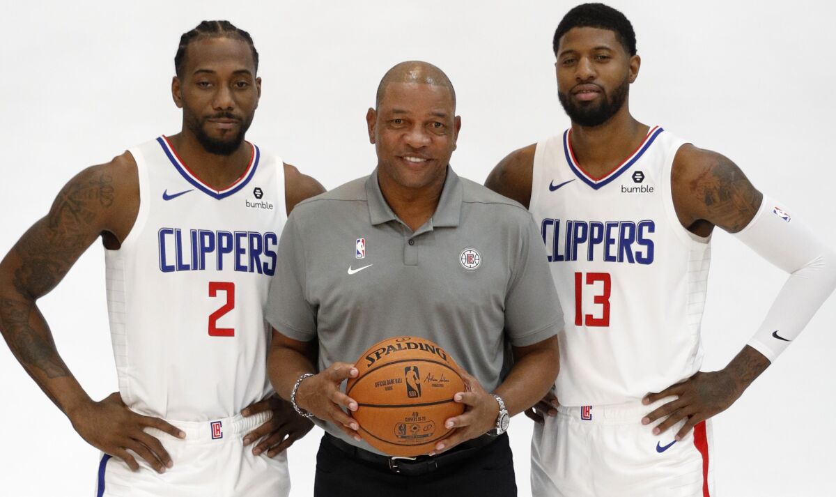 Clippers stars Kawhi Leonard, left, and Paul George pose with coach Doc Rivers for photos during the team's media day Sunday.