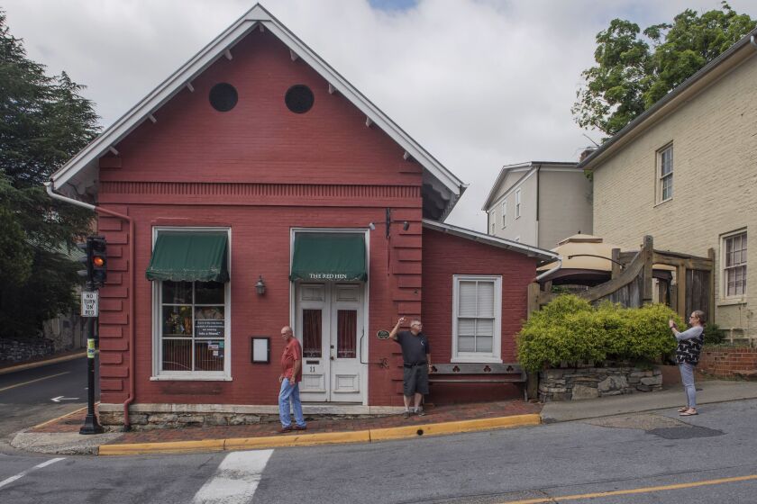 People take photos outside the Red Hen restaurant in Lexington, Va., Wednesday, June 27, 2018. The co-owner of the Virginia restaurant that refused to serve White House press secretary Sarah Huckabee Sanders has resigned from a local business group. (AP Photo/Don Petersen)