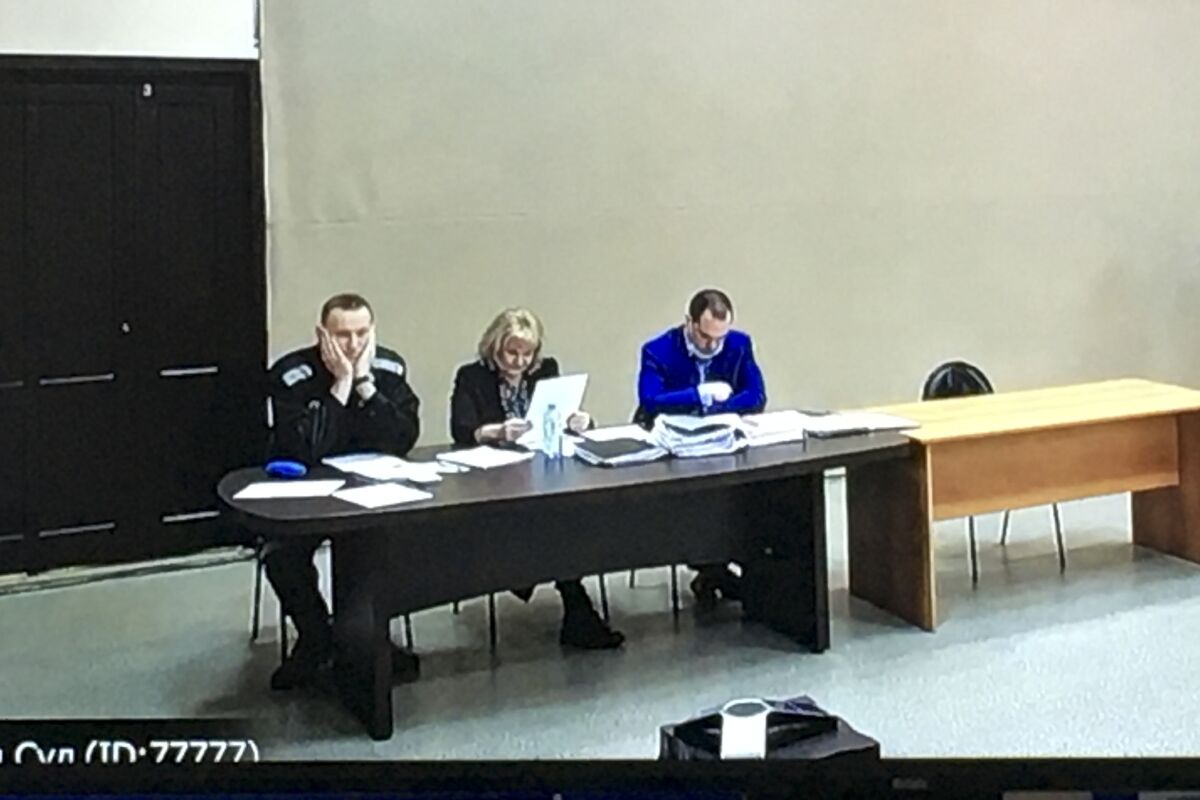 In this image provided by the Russian Federal Penitentiary Service, Russian opposition leader Alexei Navalny, left, is seen via a video link, sitting next to his layers during a court session in Pokrov, Vladimir region, about 100 kilometers (62 miles) east of Moscow, Russia, Tuesday, March 15, 2022. The Russian authorities are seeking a 13-year prison sentence for opposition leader Alexei Navalny in a trial that is widely seen as politically motivated. (AP Photo)