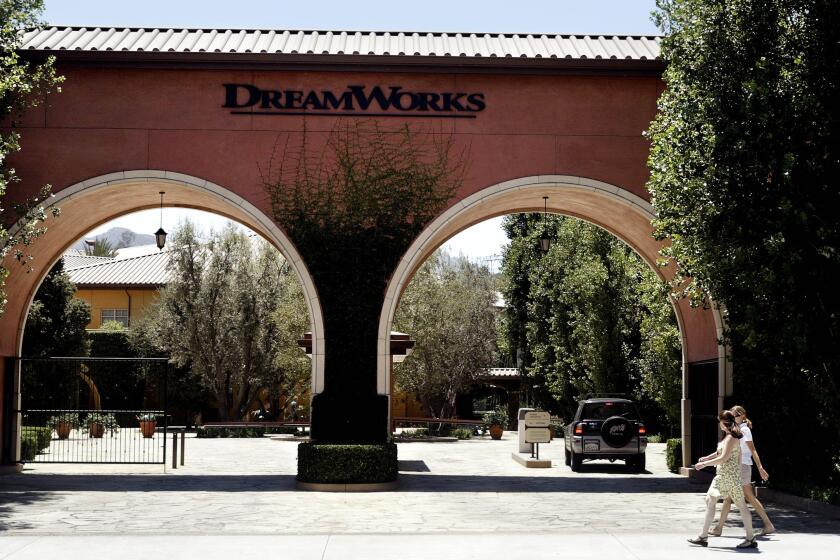People walk past the entrance to DreamWorks Animation's studio in Glendale, Calif. DreamWorks has signed a deal to sell and lease back the studio property.
