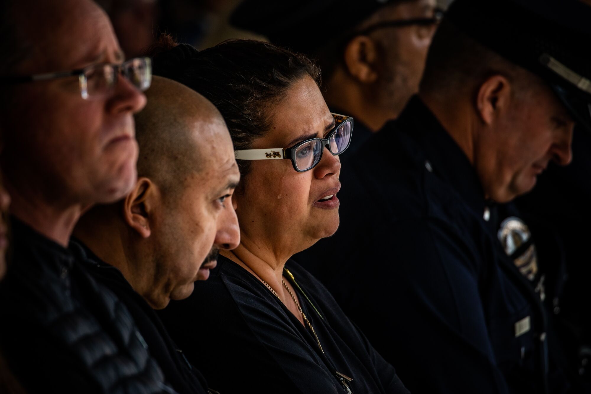 A woman cries while seated in a row of people; all wearing black.