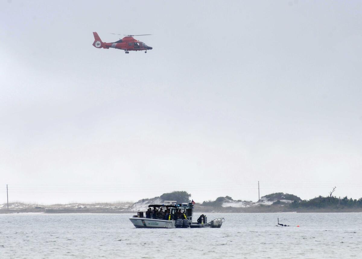 A Coast Guard helicopter flies over Santa Rosa Sound near Navarre, Fla., as divers search the waters below for a Black Hawk helicopter that went down Tuesday evening with 11 service members aboard.