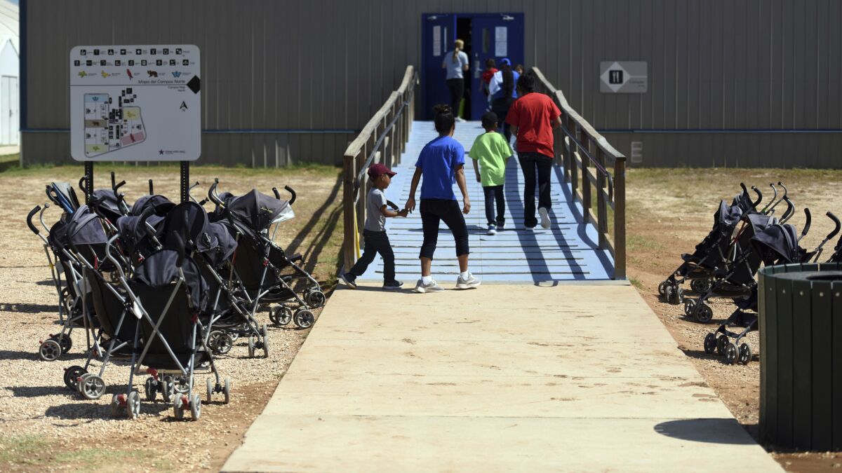 In this Aug. 2018 photo, provided by U.S. Immigration and Customs Enforcement, immigrants walk into a building at South Texas Family Residential Center in Dilley, Texas. The facility is one of three across the U.S. that hold migrant families in custody.