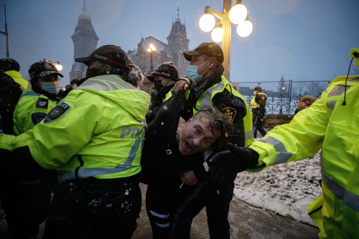 A man is arrested by police as protesters and supporters gather as a protest against COVID-19 measures that has grown into a broader anti-government protest continues to occupy downtown Ottawa, Ontario, on Thursday, Feb. 17, 2022. (Cole Burston/The Canadian Press via AP)