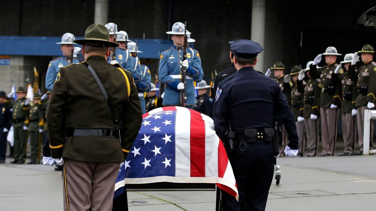 The flag-draped casket bearing the body of Tacoma Officer Reginald "Jake" Gutierrez is carried outside the Tacoma Dome before a public memorial service in Tacoma, Wash., on Dec. 9.