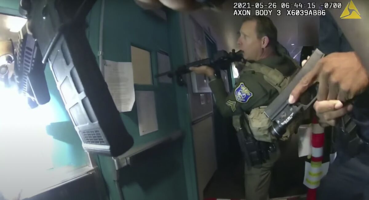 Deputies approach a set of doors with their weapons drawn.