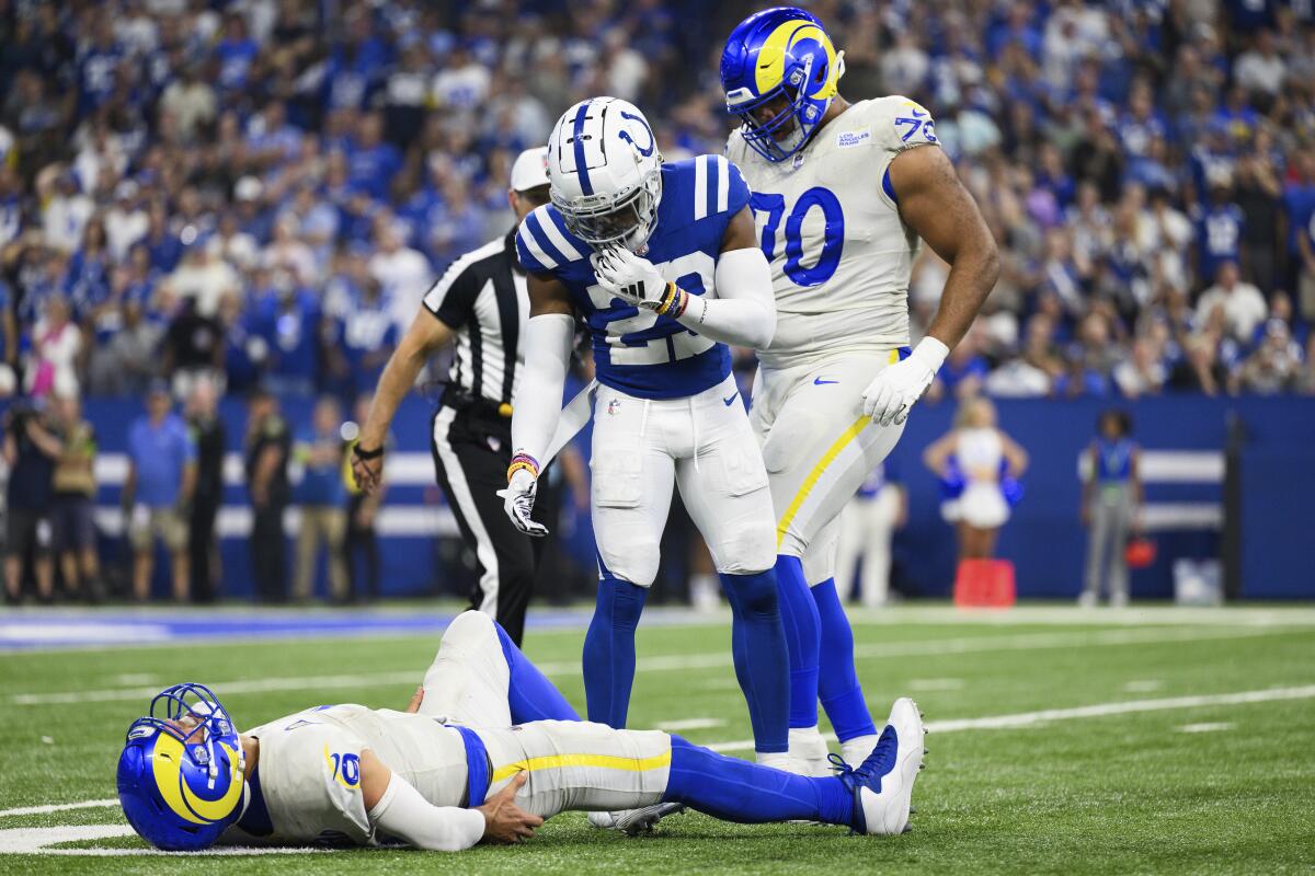 Colts cornerback Kenny Moore II (23) tries to assist Rams quarterback Matthew Stafford (9), who had injured his hip.