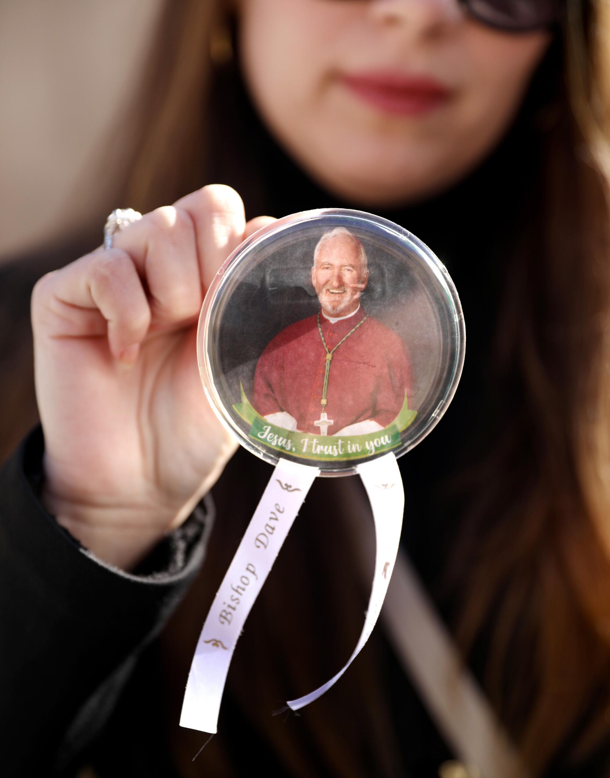 A woman holds up a button with a picture of Bishop  O'Connell