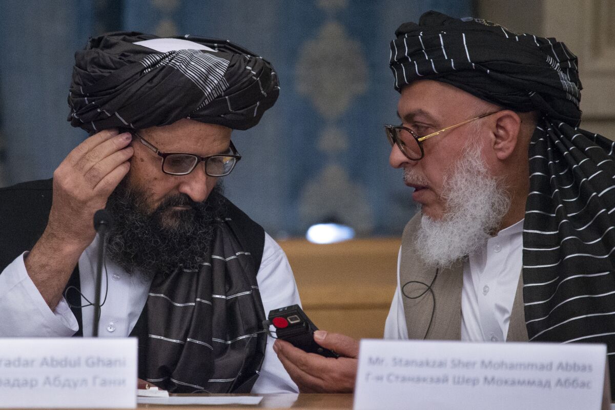 FILE - In this May 28, 2019, file photo, Mullah Abdul Ghani Baradar, the Taliban group's top political leader, left, and Sher Mohammad Abbas Stanikzai, the Taliban's chief negotiator, talk to each other during a meeting in Moscow, Russia. Taliban officials say several of the group’s members have been freed from Afghan jails, including former shadow governors, the first move of its kind since a peace deal that seemed imminent was declared “dead” and just days after a U.S. envoy met with Mullah Abdul Ghani Baradar and other top Taliban leaders in the Pakistani capital of Islamabad. (AP Photo/Alexander Zemlianichenko, File)