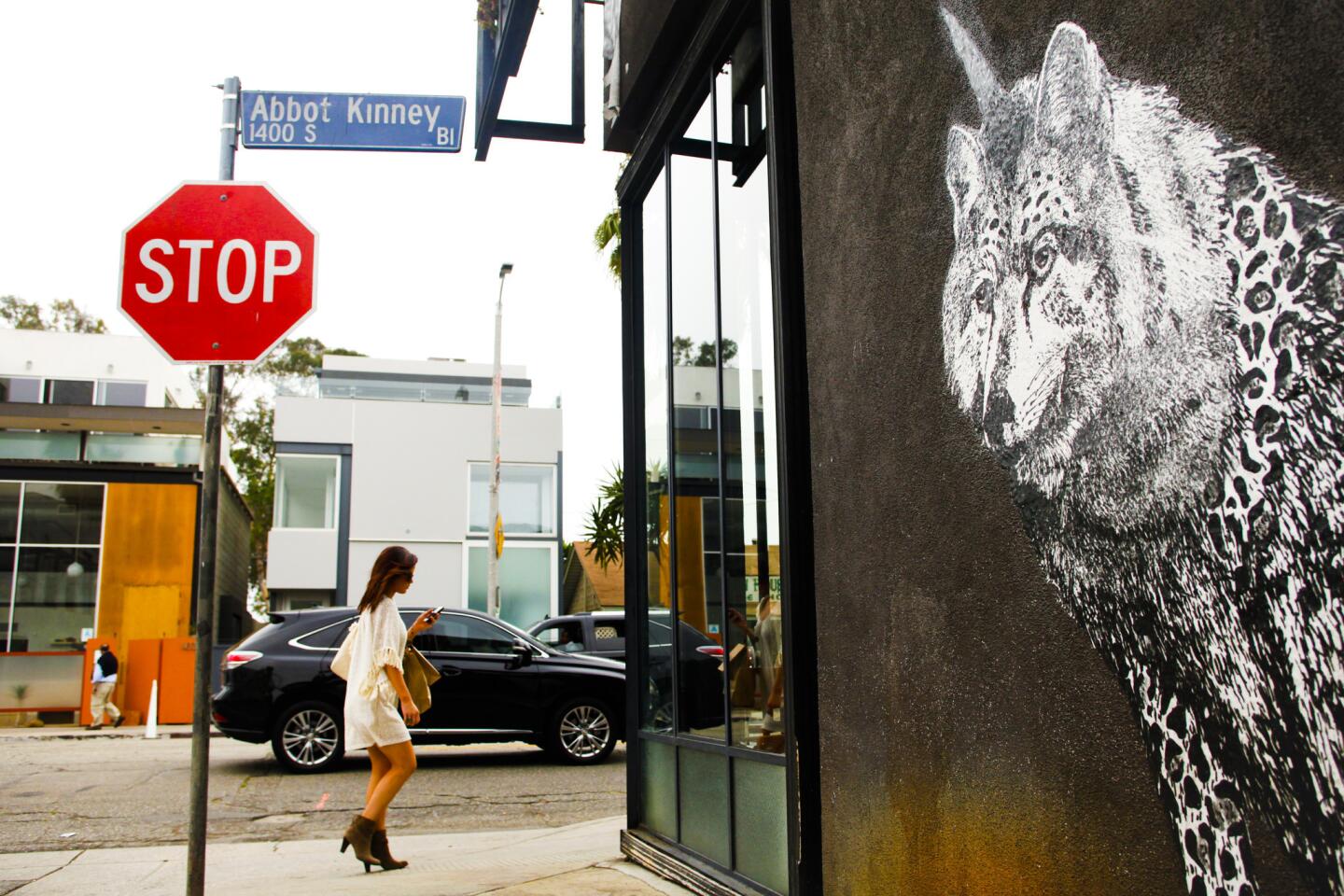 A woman walks past street art on Abbot Kinney in Venice. Over recent decades the street has increasingly attracted tony stores and restaurants that are drawing tourists from around the world but are pushing out some longtime residents and businesses.