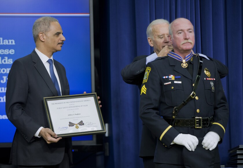 FILE - In this Feb. 11, 2015, file photo, Attorney General Eric Holder and Vice President Joe Biden award the Medal of Valor to Sgt. Jeffrey Pugliese from the Watertown, Mass., Police Department, during a ceremony in the Old Executive Office Building at the White House Complex in Washington. Pugliese, a suburban Boston police officer who became a national hero in 2013 when he tackled one of the Boston Marathon bombers, retired from the only job he ever wanted on Monday June 1, 2021, after more than 41 years on the force. (AP Photo/Pablo Martinez Monsivais, File)