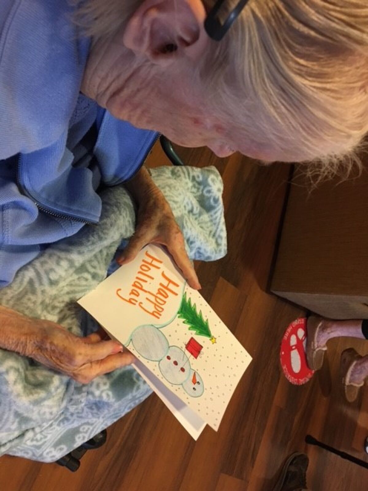 A senior at Brookdale Carmel Valley opens one of the holiday cards made by a Junior Optimist.