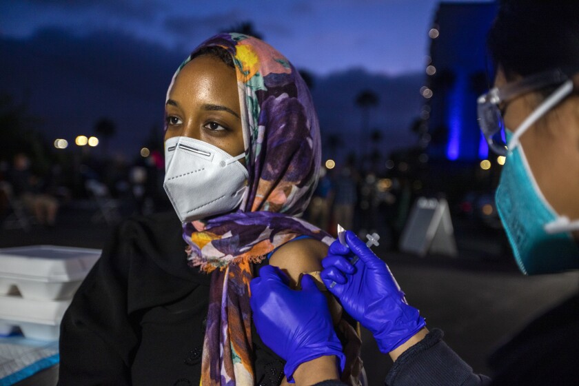 Sara Ahmed, 29, of Anaheim gets  vaccinated by EMT Daniella Gochuico