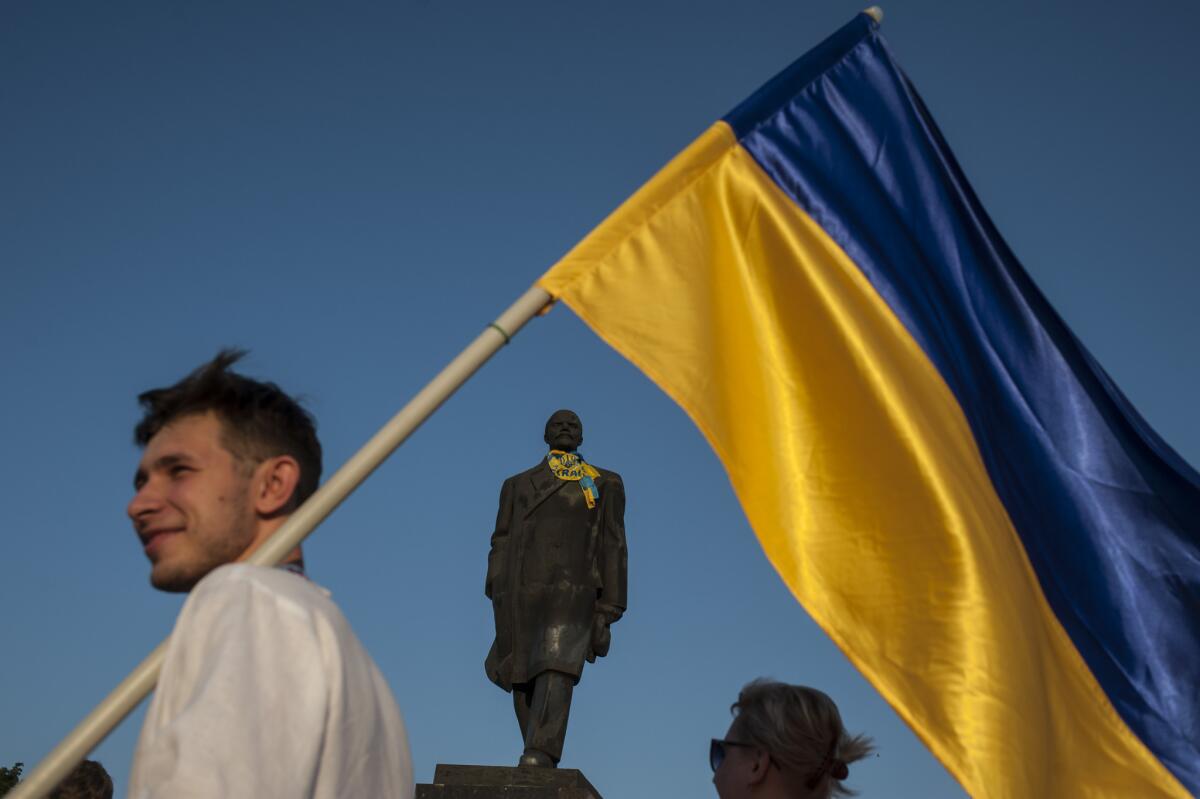 A Ukrainian government supporter with a national flag at a statue of Soviet founder Vladimir Lenin in formerly separatist-held Kramatorsk, eastern Ukraine.