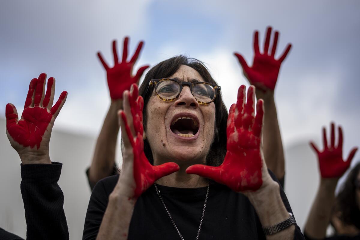 Family and supporters of hostages held in the Gaza Strip scream and hold up their hands, painted red to symbolize blood.