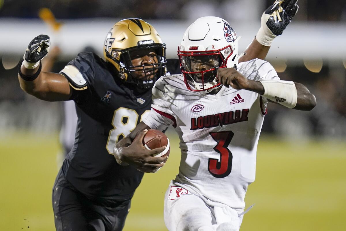Central Florida defensive end Josh Celiscar, left, closes in on Louisville quarterback Malik Cunningham (3) during the second half of an NCAA college football game, Friday, Sept. 9, 2022, in Orlando, Fla. (AP Photo/John Raoux)