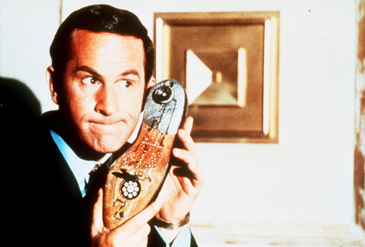 Don Adams holding a shoe phone to his ear.