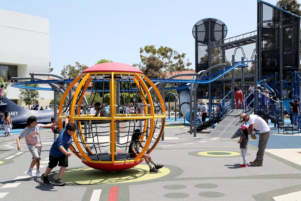 Children and adults enjoy the new playground at Lions Park in Costa Mesa, July 17, 2021.