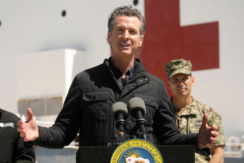 California Governor Gavin Newsom (C), flanked by Director Mark Ghilarducci, Cal OES, (L) and Admiral John Gumbleton, United States Navy, speaks in front of the hospital ship USNS Mercy after it arrived into the Port of Los Angeles on March 27, 2020. - The USNS Mercy, a giant US naval hospital ship, arrived in Los Angeles on March 27, where it will be used to ease the strain on the city's coronavirus-swamped emergency rooms. (Photo by Carolyn Cole / POOL / AFP) (Photo by CAROLYN COLE/POOL/AFP via Getty Images)