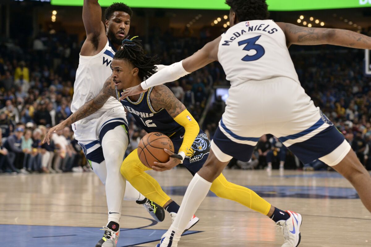 Memphis Grizzlies guard Ja Morant drives between Minnesota Timberwolves forward Jaden McDaniels and guard Malik Beasley.