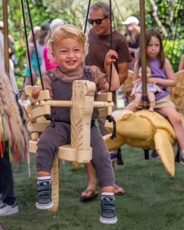 Children ride on suspended wooden animals