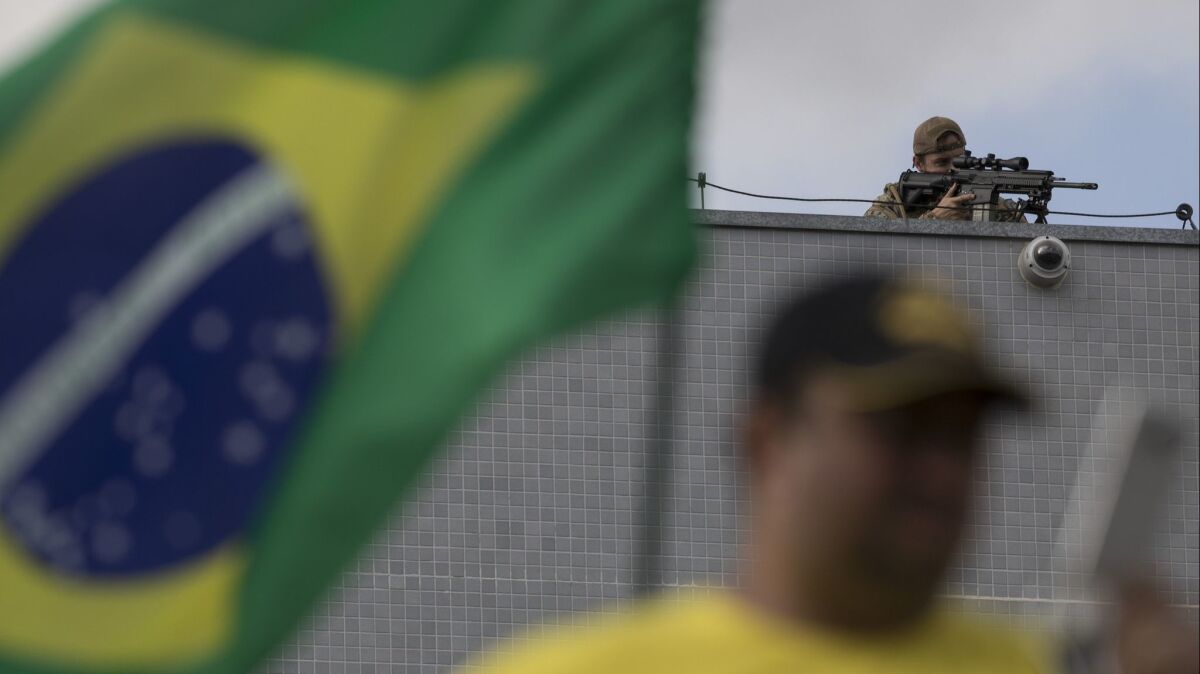 A federal police sniper aims his weapon as demonstrators protest against Brazil's former President Luiz Inacio Lula da Silva in front of the Federal Police Department in Curitiba, Brazil on Friday.