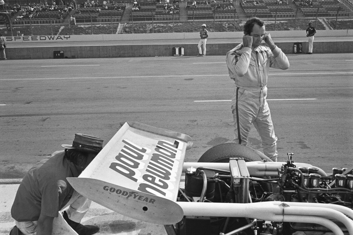 Bob Bondurant stands next to a race car.