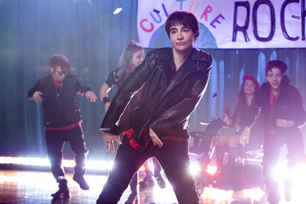 Nasim Pedrad as a teenage boy dances onstage in a leather jacket.