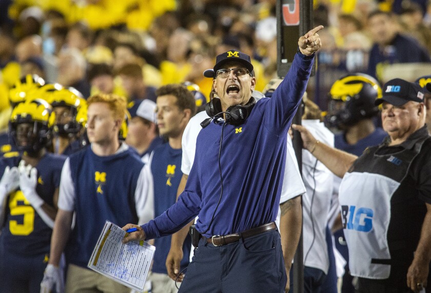 Michigan coach Jim Harbaugh signals a Michigan first down on the sideline during the fourth quarter of the team's NCAA college football game against Washington in Ann Arbor, Mich., Saturday, Sept. 11, 2021. (AP Photo/Tony Ding)