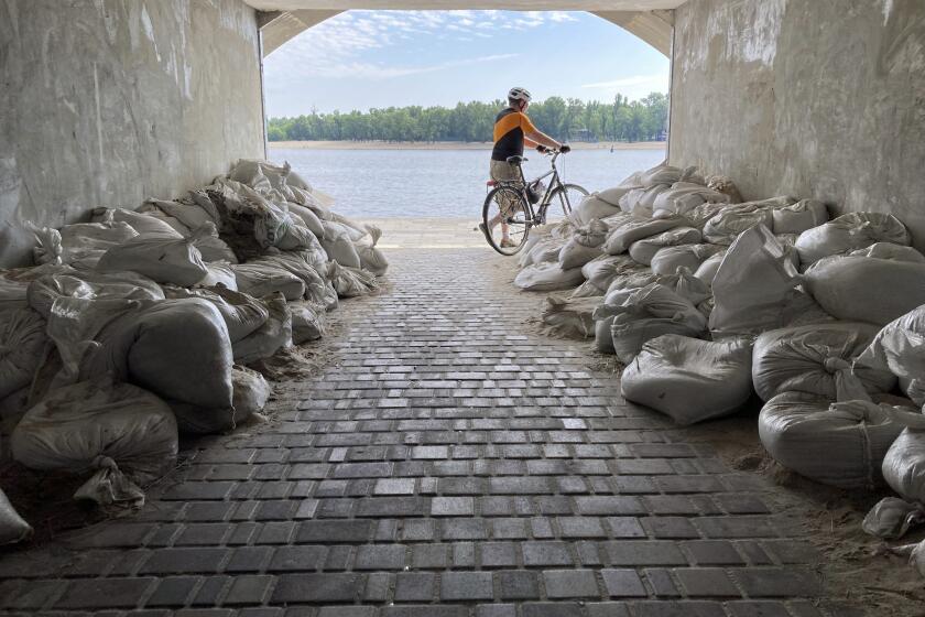 A Sunday morning cyclist emerges from a sandbagged tunnel next to the Dnipro River in Kyiv, Ukraine, Sunday, July 10, 2022. The war's reminders are everywhere as Russian forces pound away at communities in Ukraine's industrial heartland to the east. (AP Photo/Cara Anna)