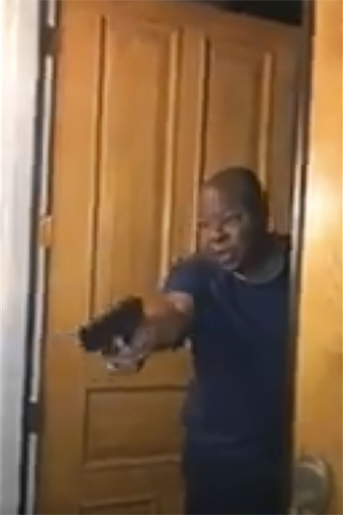 In a still from video, Jackie Lacey's husband points a gun at Black Lives Matter protesters outside his front door