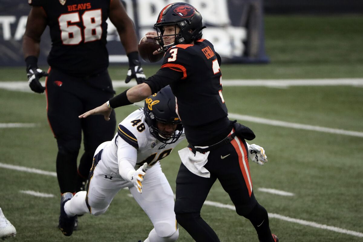 Oregon State quarterback Tristan Gebbia throws a pass before being brought down by Cal linebacker Orin Patu on Nov. 21, 2020.