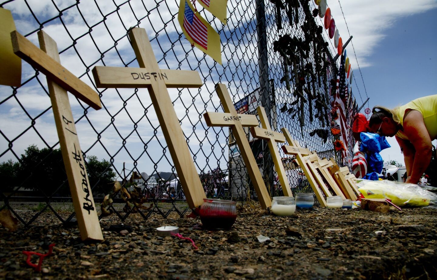 Nineteen crosses lean against the fence surrounding Fire Station 7.