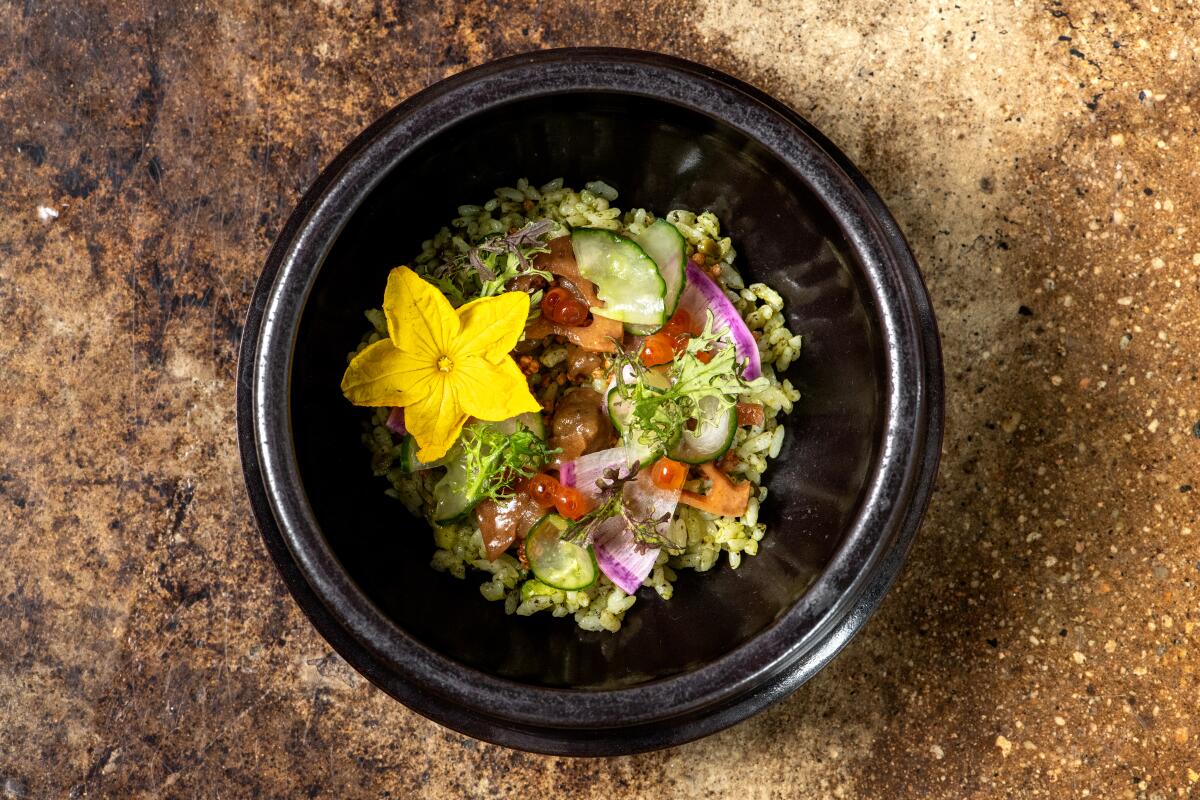 An overhead photo of Kinn's elaborate summertime bibimbap with seaweed rice adorned with flowers, ikura and vegetables.