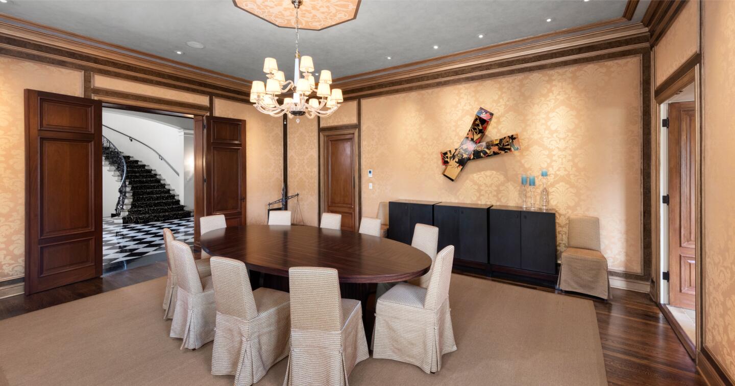 Wood doors slide open to a room with a round table and a chandelier.