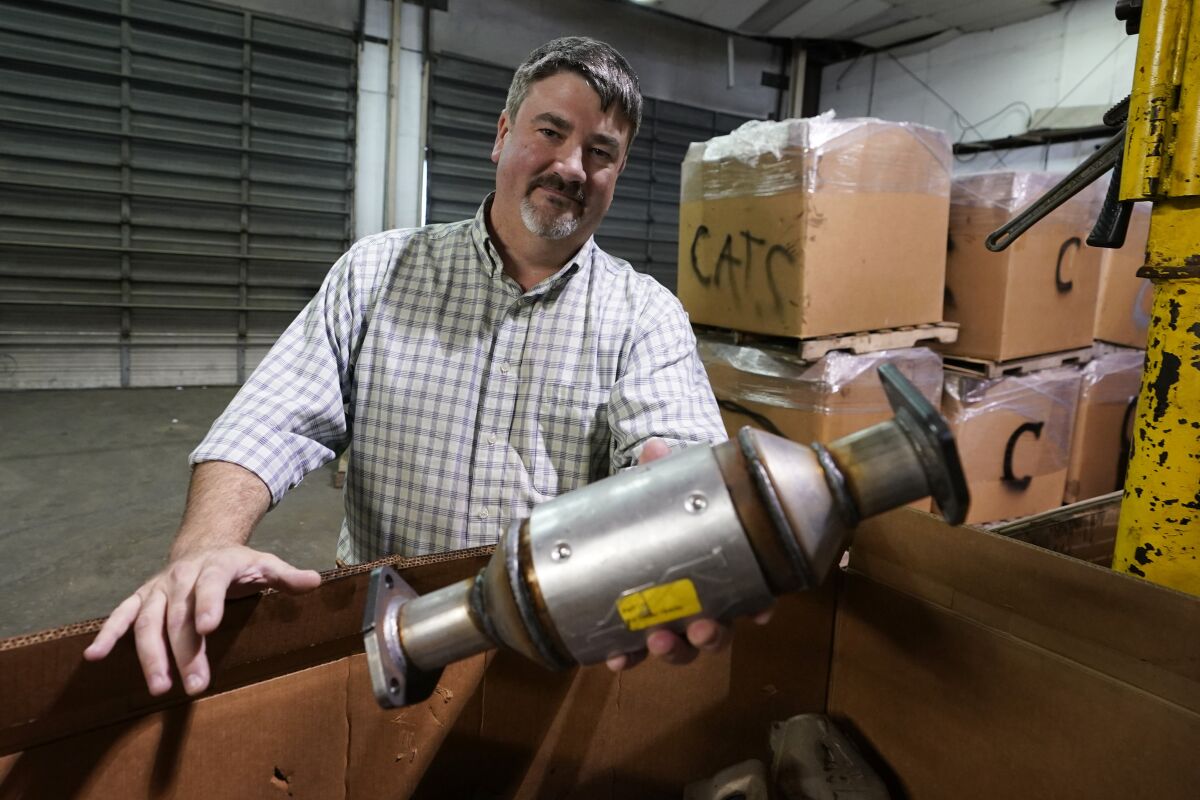 Troy Webber holds a used catalytic converter that was removed from one of the cars at his salvage yard in Virginia.