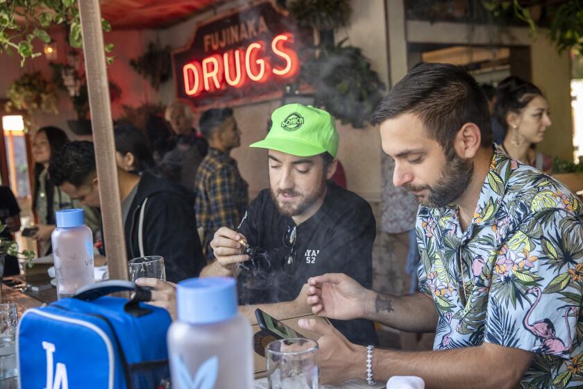 WEST HOLLYWOOD, CALIF. -- TUESDAY, OCTOBER 1, 2019: Patrons Connor Cacciottolo, left, and friend Tim Hitpas, right, enjoy a joint at Lowell Cafe, a new restaurant and cannabis bar in West Hollywood allows diners to smoke marijuana inside and out thanks to a new license issued by the city in West Hollywood, Calif., on Oct. 1, 2019. (Brian van der Brug / Los Angeles Times)