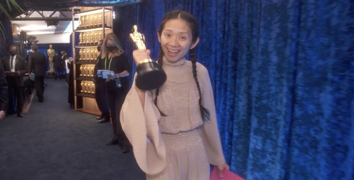 Chloe Zhao holding one of her Oscars for "Nomadland" backstage.