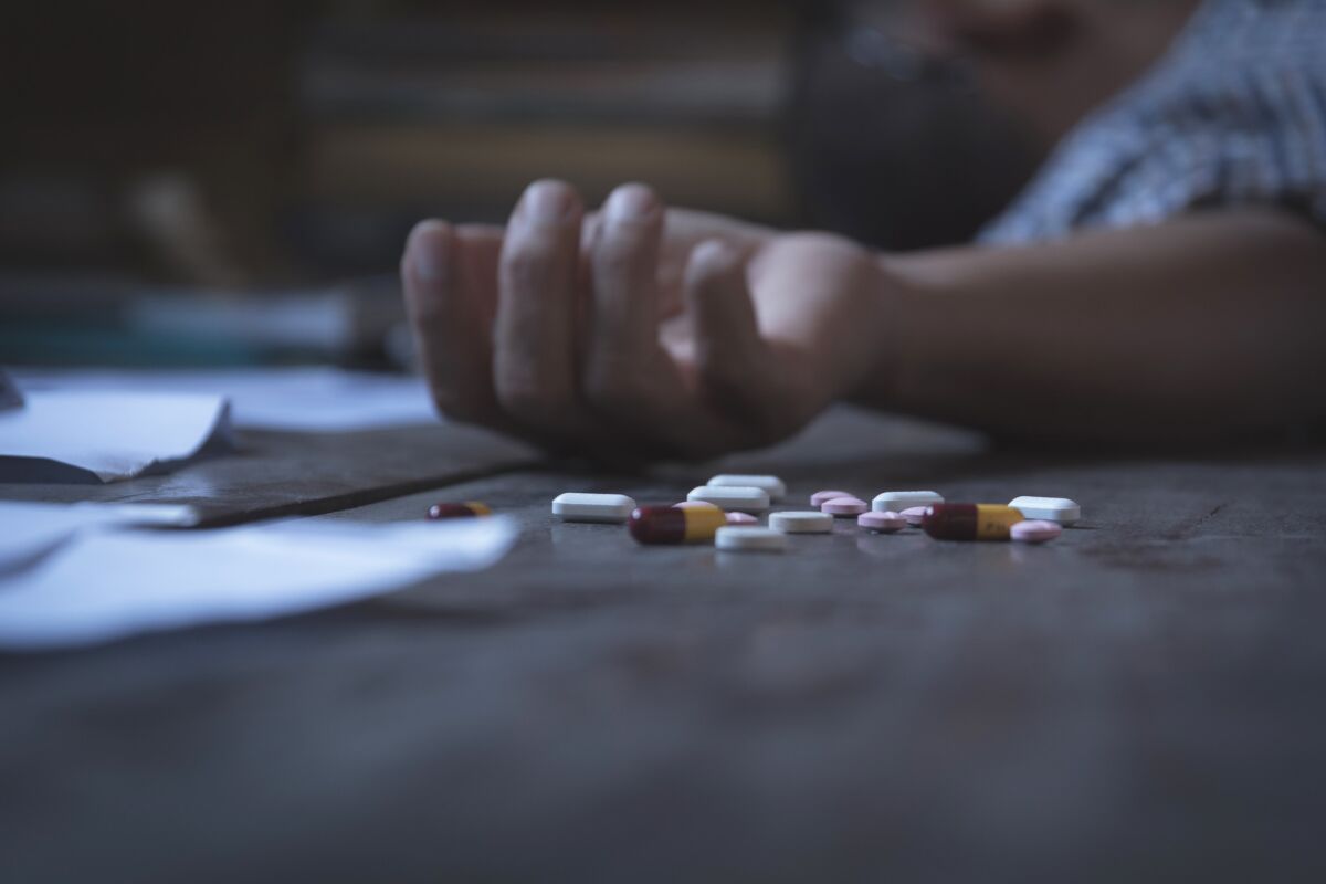 An overdose victim lies next to pills