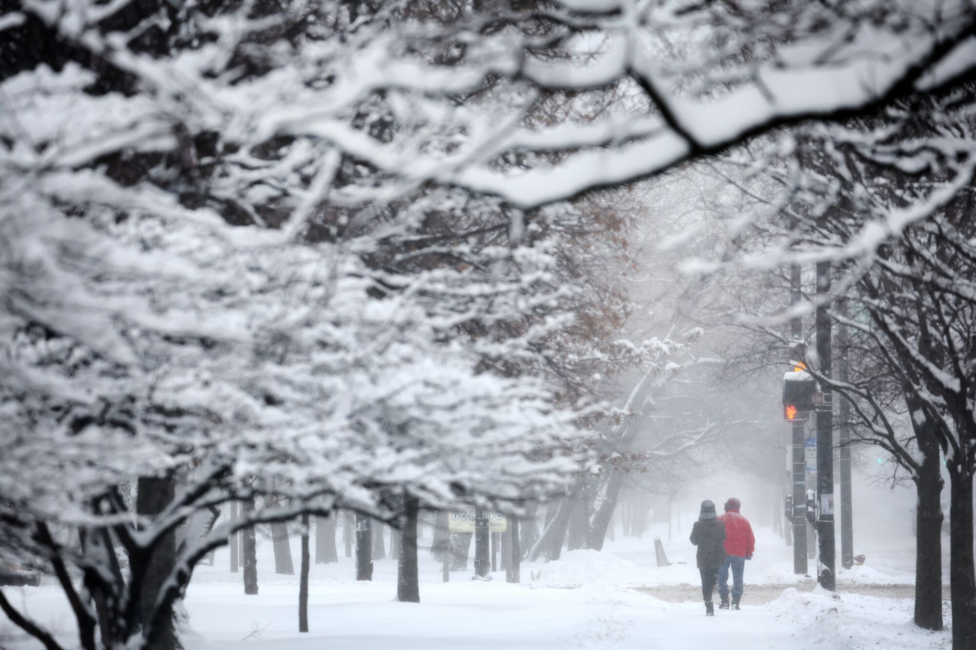 People walk down a snow-covered sidewalk