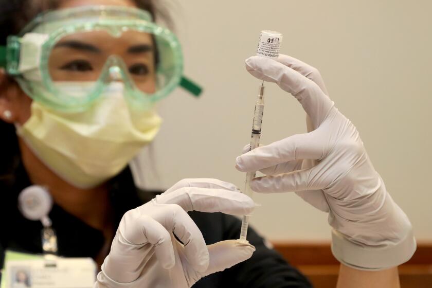 Clinical pharmacist Stephanie Chao fills a syringe with a Pfizer-BioNTech COVID-19 vaccine at Hoag Hospital in Newport Beach on Thursday.