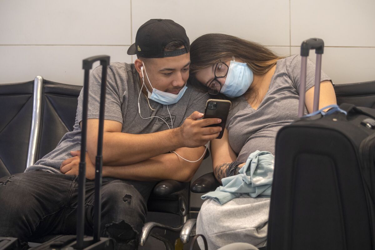 A man and a woman look at a cellphone at LAX.