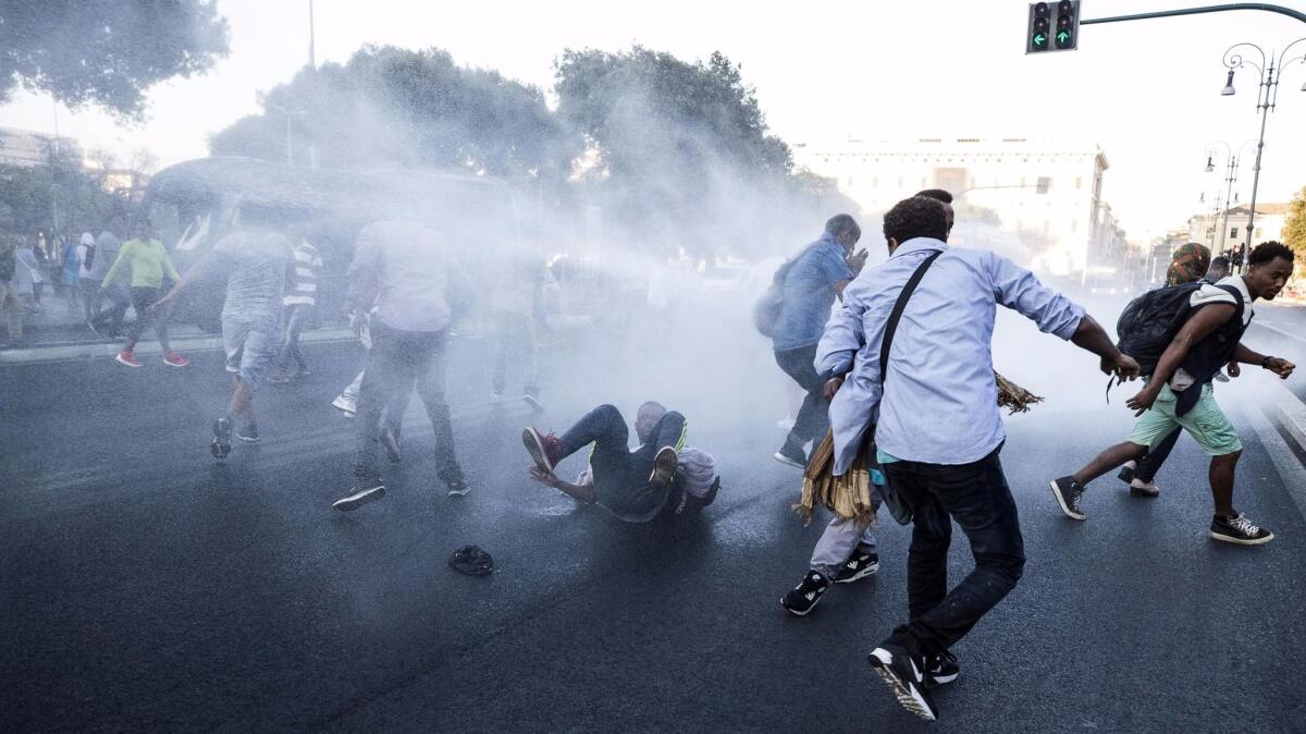 Italian law enforcement officers use a water cannon to disperse migrants in central Rome on Thursday.